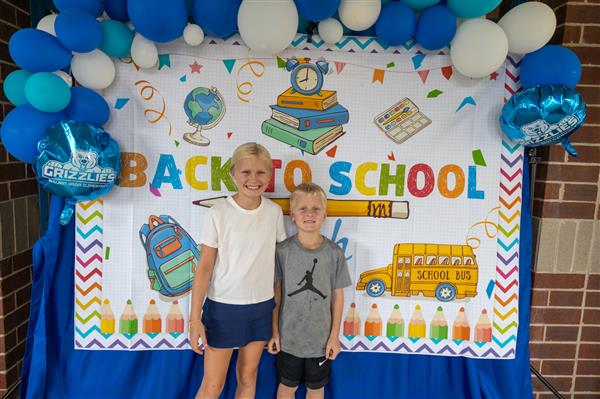 two students in front of a back to school bash sign